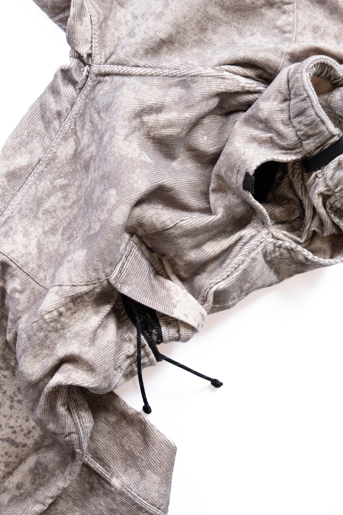A close-up of the cargo pants showing the textured material, drawstring, on a white background.