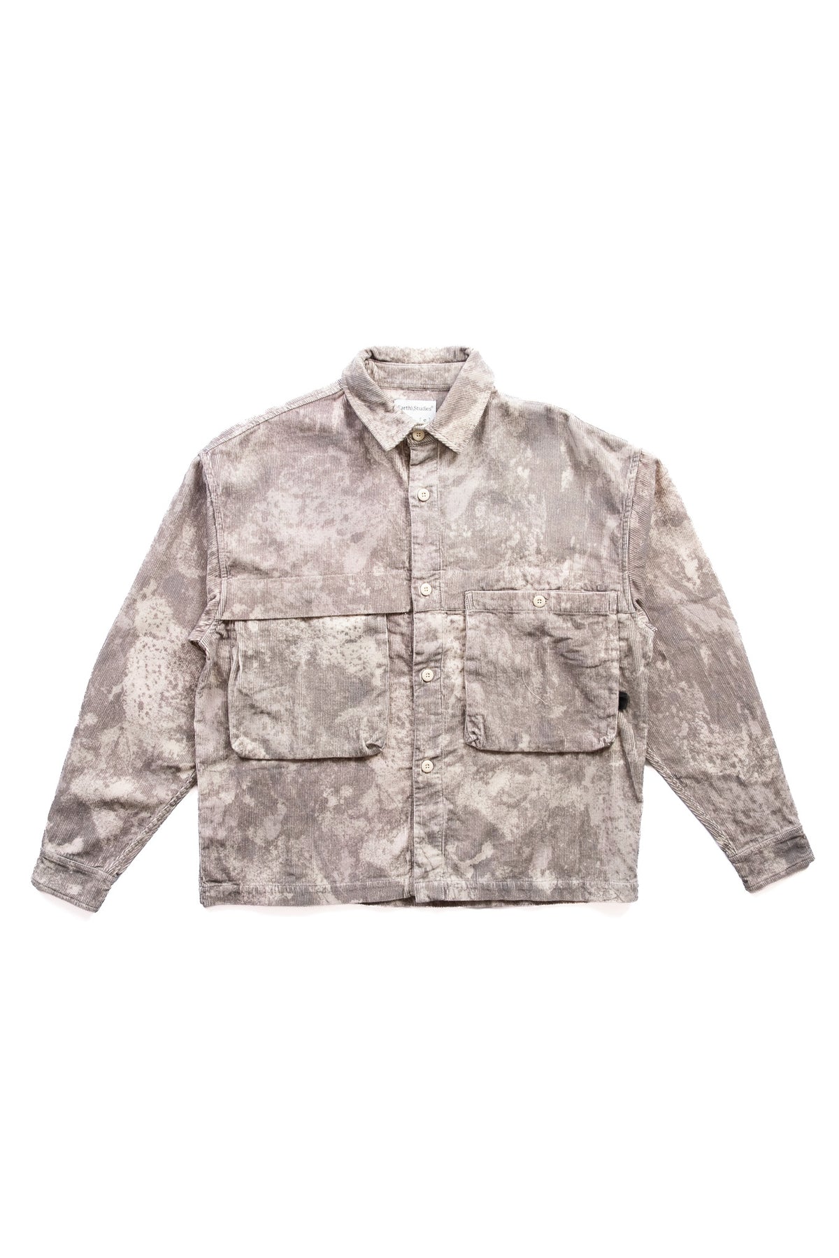 A long-sleeve button-up shirt with a mottled, corduroy camouflage pattern in shades of beige, gray, and brown, featuring two large front flap pockets.