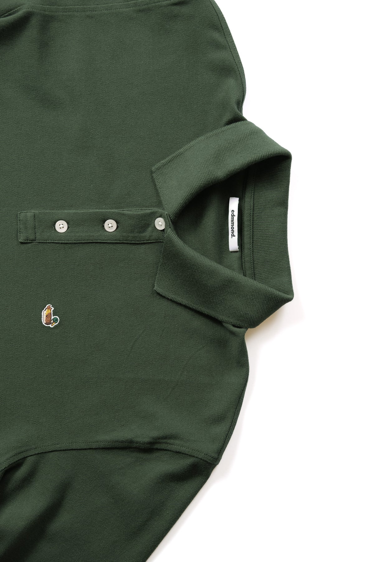 Close-up of a dark green long sleeve polo with a three-button placket, a small embroidered duck logo on the chest.