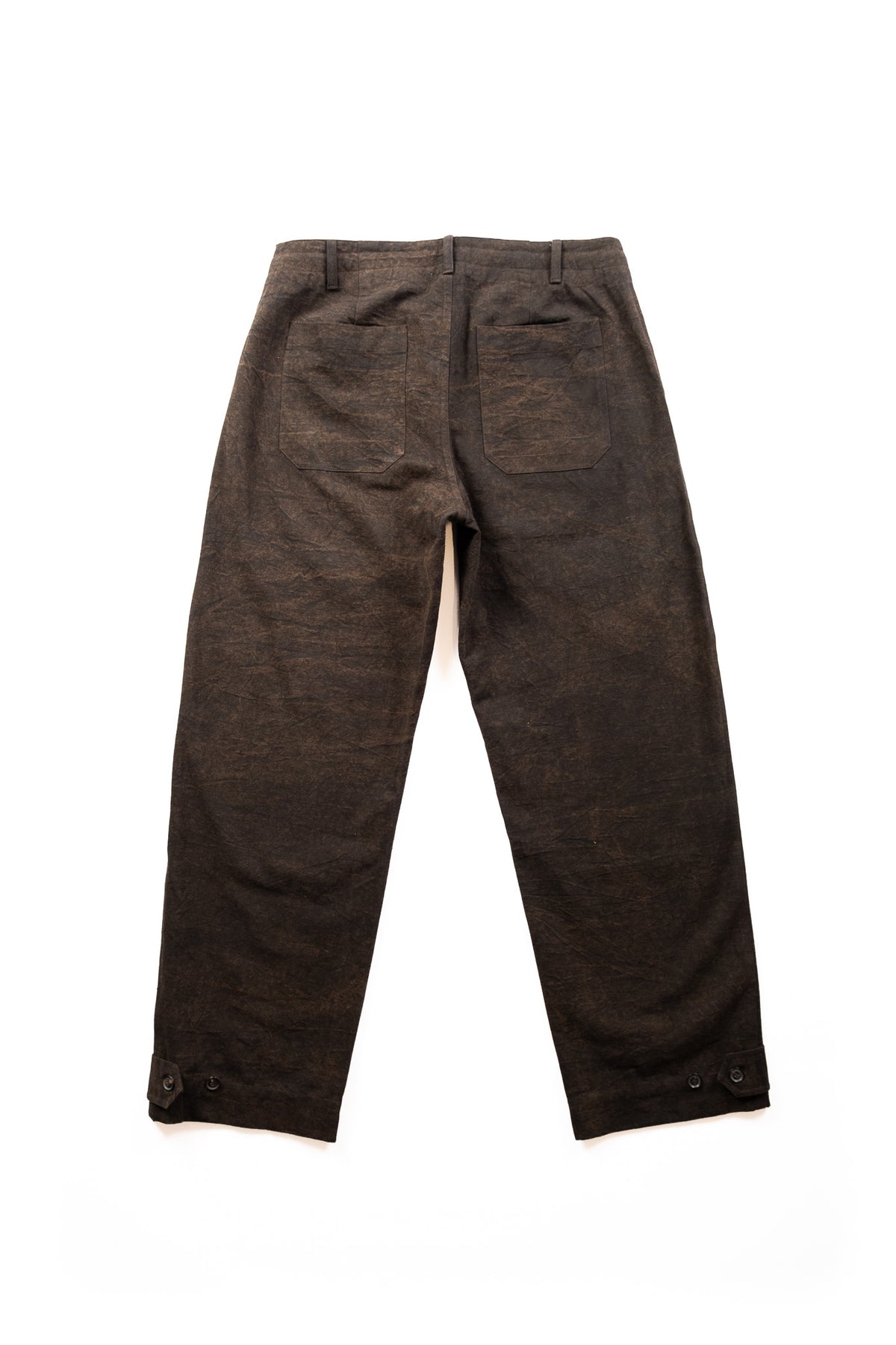 A pair of dark brown trousers with back patch pockets, and a textured, slightly mottled finish, shown from the back on a plain white background.