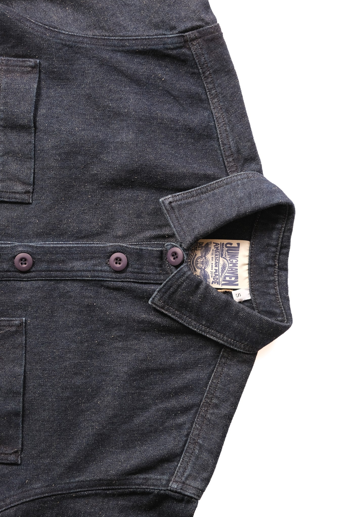 close up of dark denim button up laid on a white background