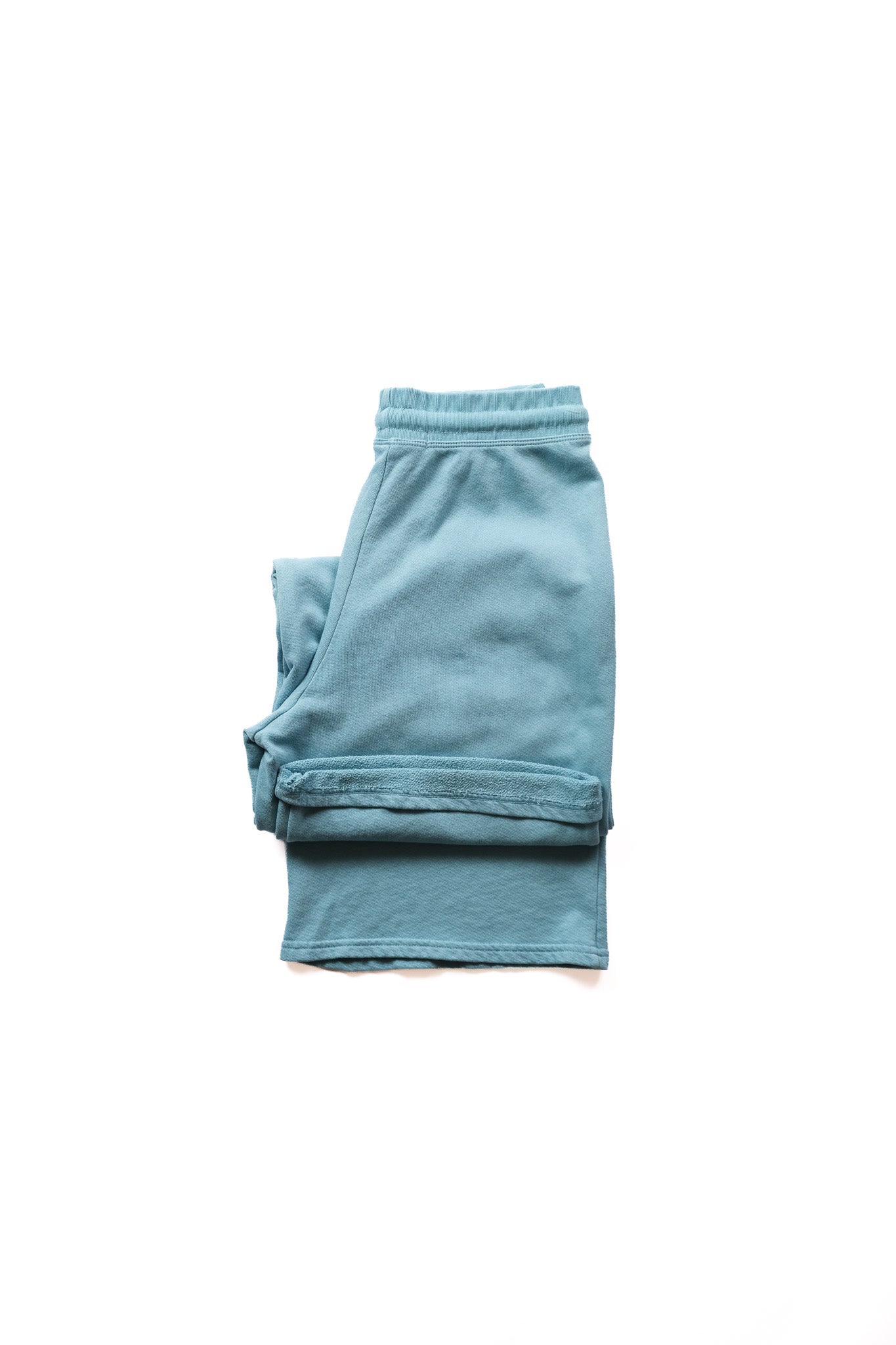 Folded pair of teal blue wide legged sweatpants
