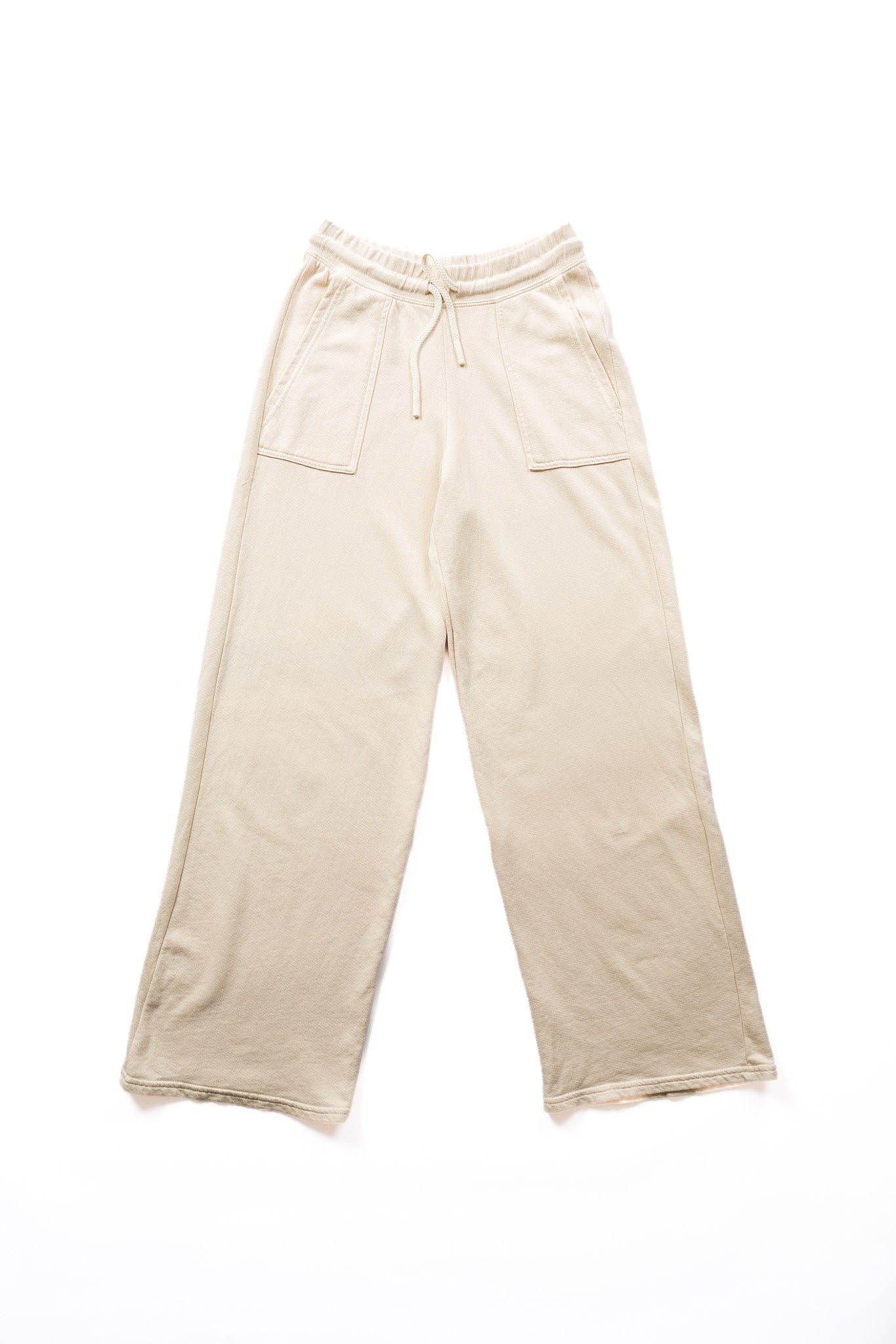 A pair of wide-leg, sweatpants in a light beige featuring an elastic waistband with a drawstring and two front patch pockets, laid flat on a white background.