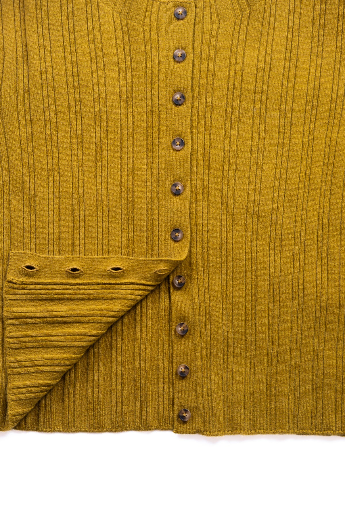 Close-up of a yellow green ribbed knit cardigan with a button front and a the hem folded up to show the button shown on a white background.