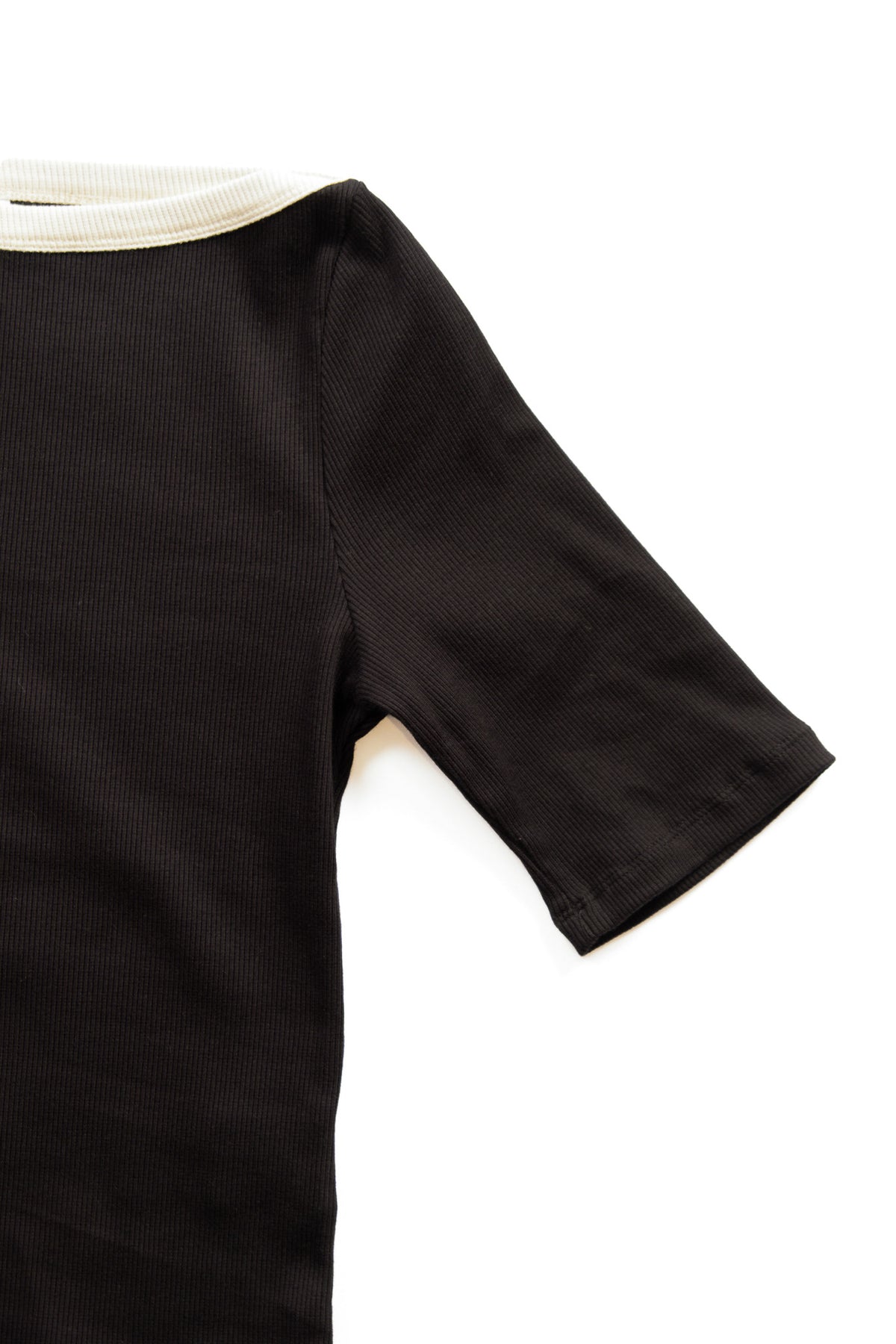 Close-up of a black ribbed short-sleeve top with a cream ribbed collar, shown on a plain white background.
