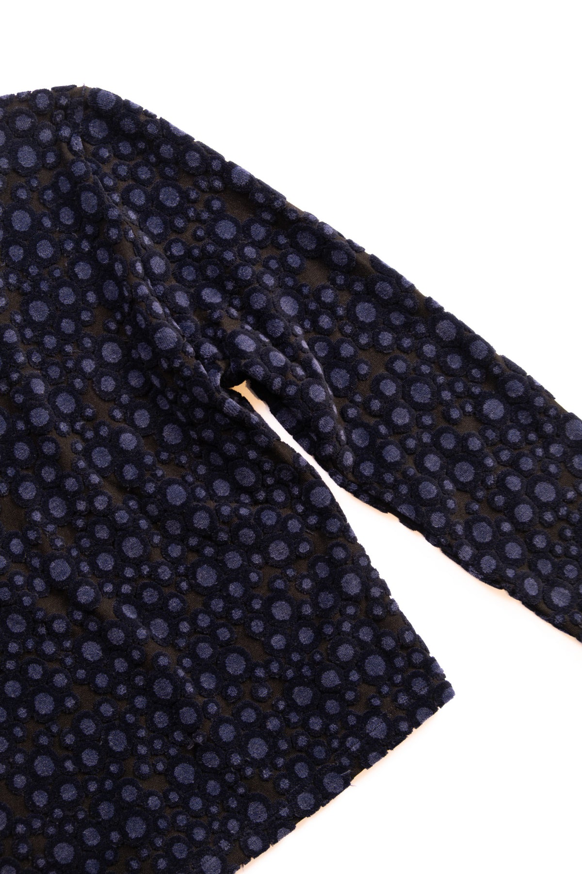 A close-up of a dark navy blue fabric with a repeating pattern of small navt circles, shown on a plain white background.