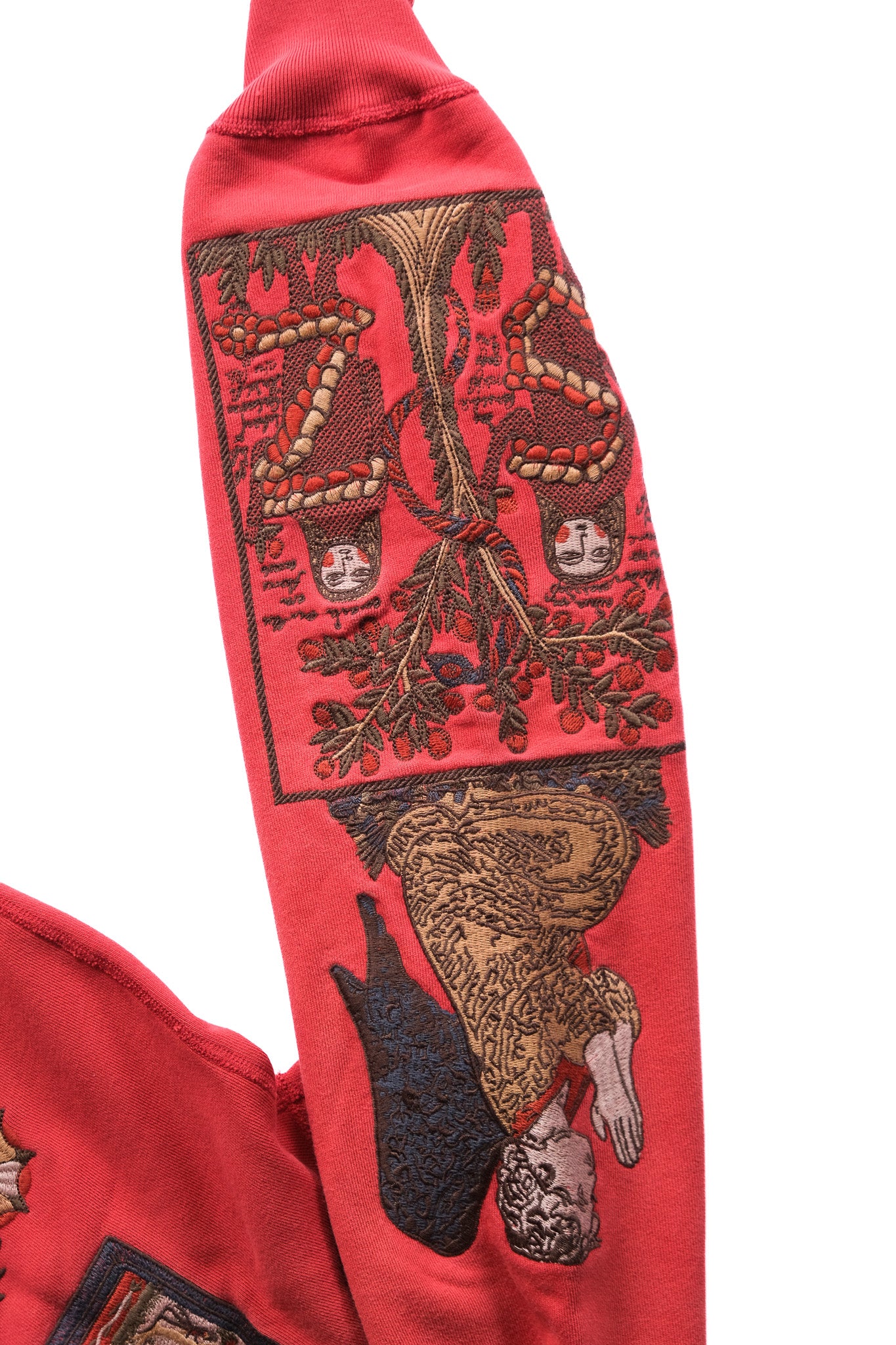 A close-up of a red quarter zip sleeve featuring a large, detailed embroidery of angel imagery