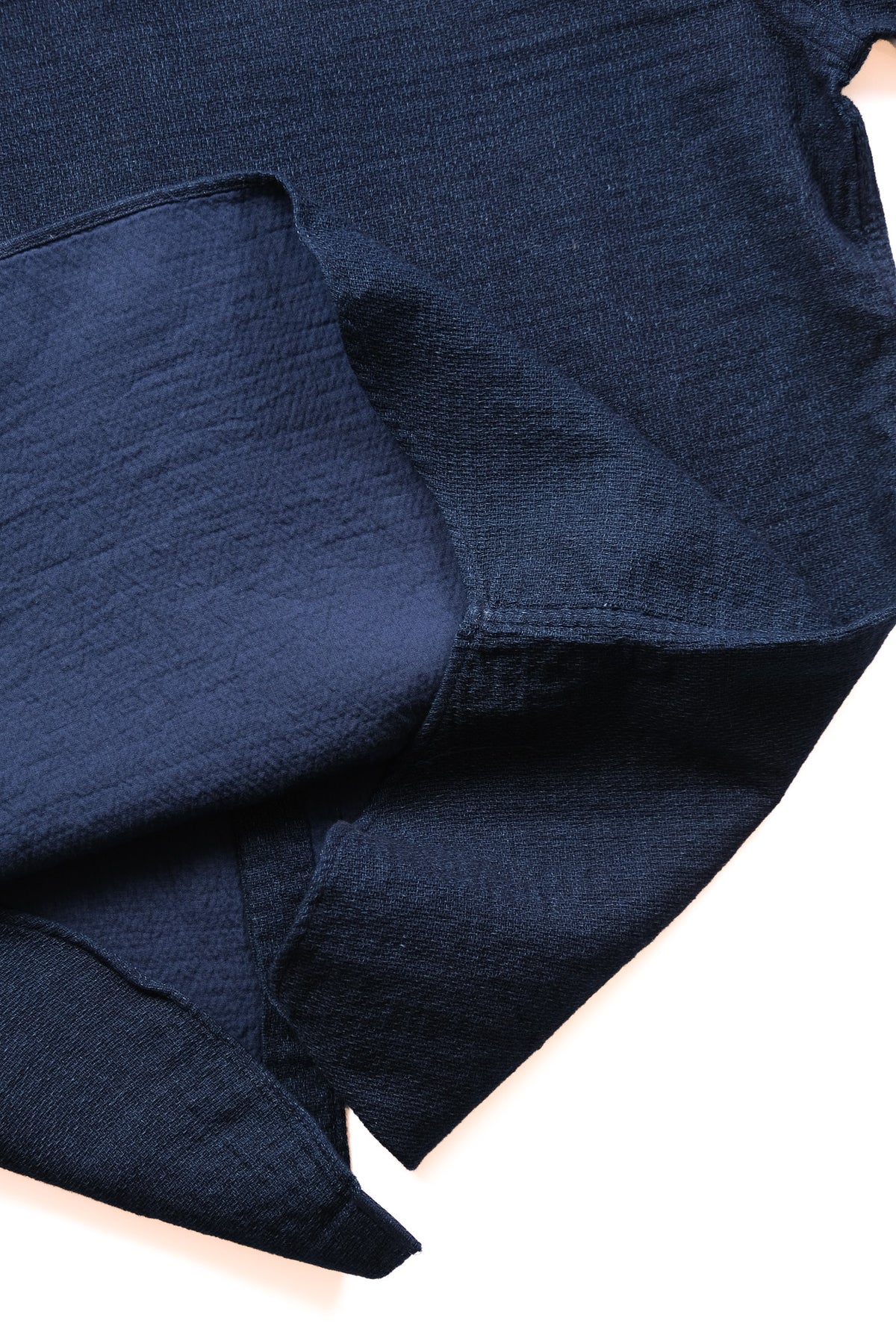 A close-up of dark navy blue textured fabric draped against a plain white background.