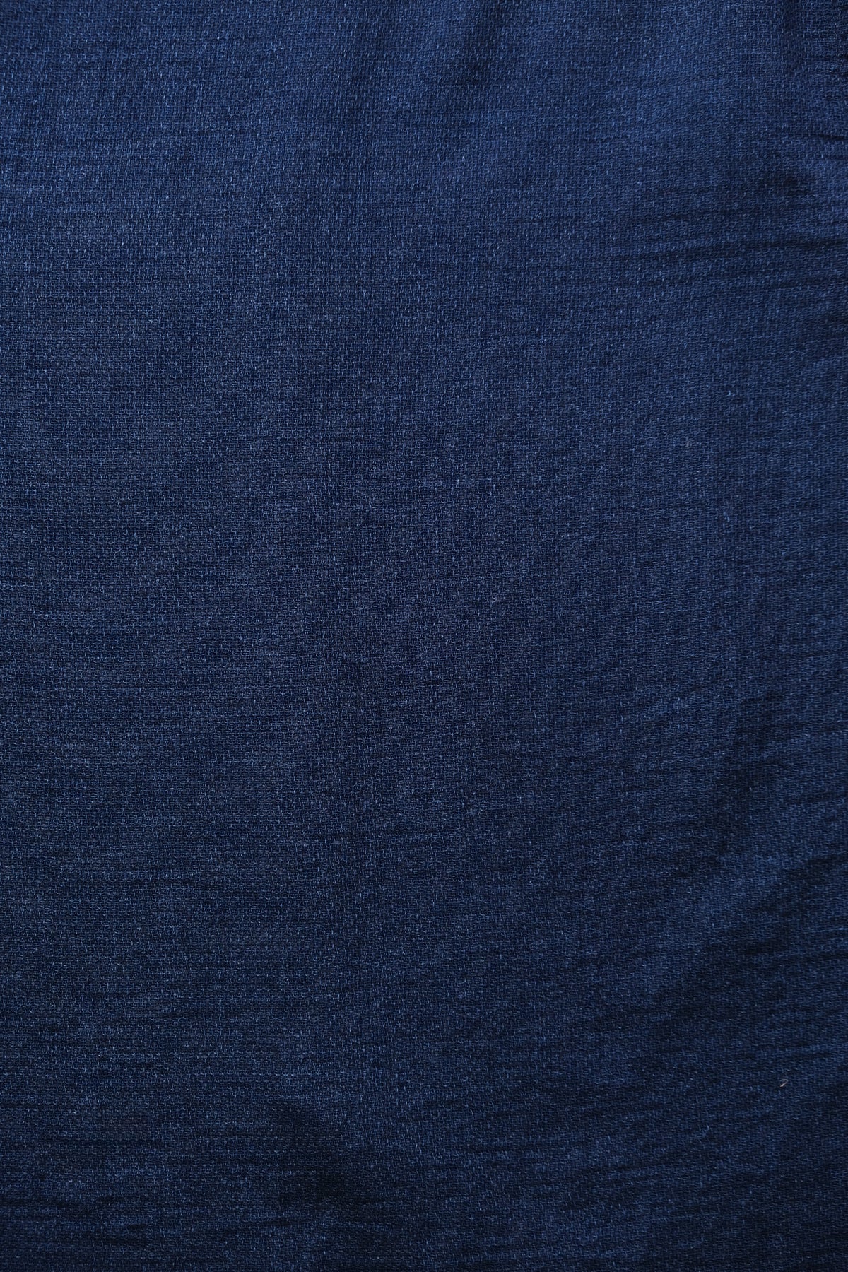 A close-up of dark navy blue textured fabric with a fine woven pattern.