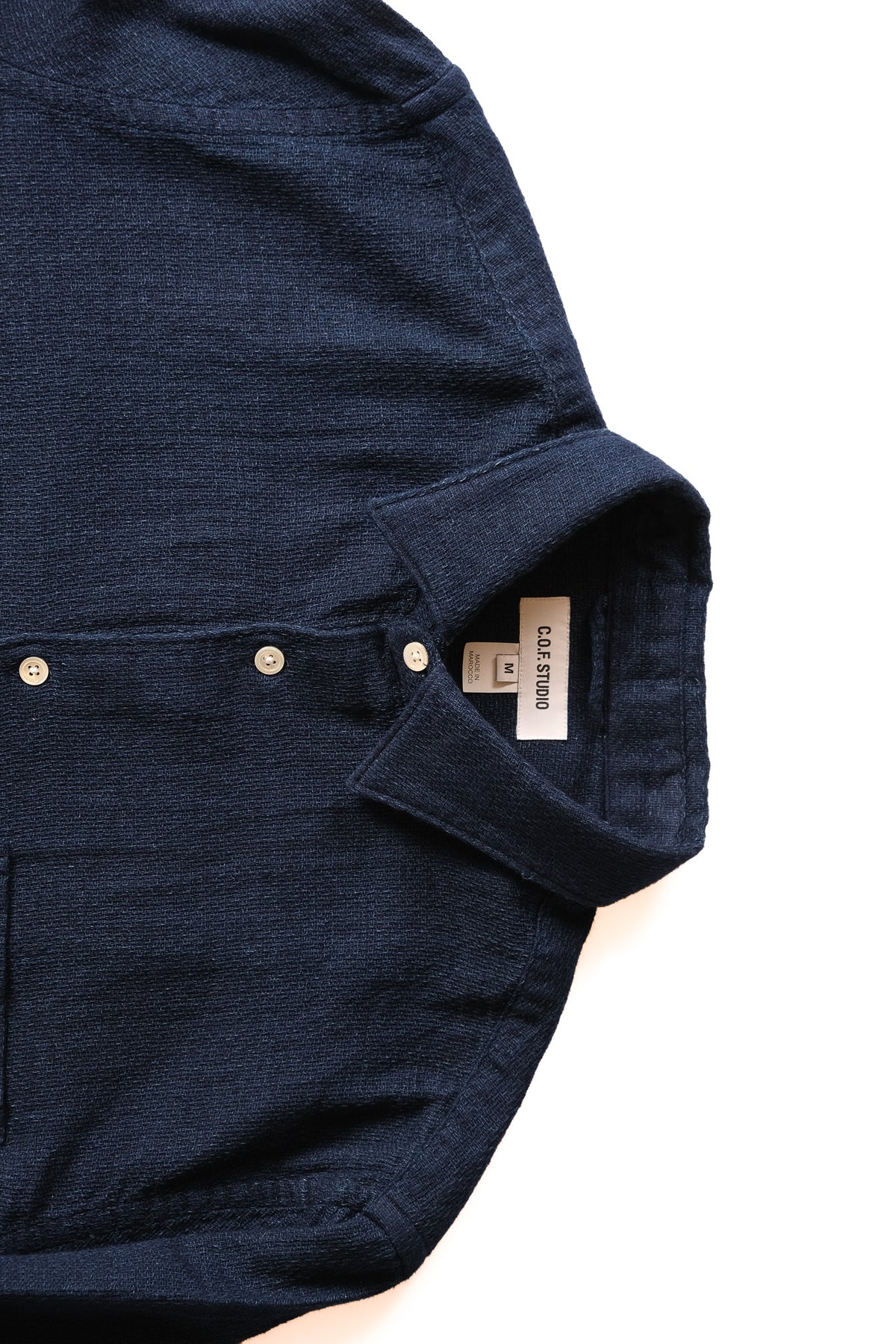 Close-up of a dark indigo blue textured button-up shirt with a collar.