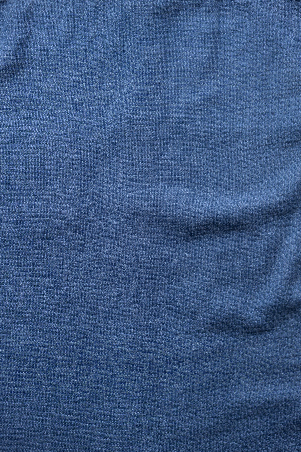 A close-up of textured blue knit fabric with soft folds and a fine ribbed pattern.
