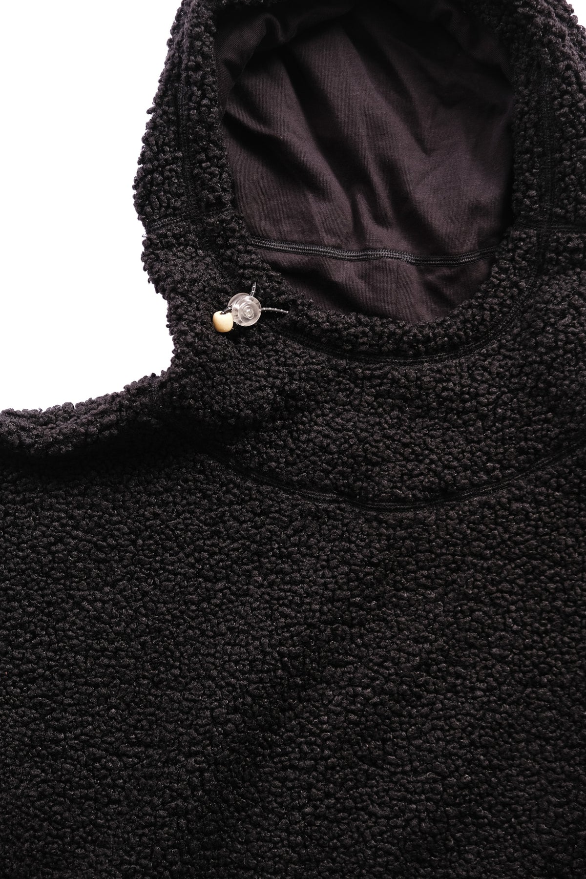 Close-up of a black sherpa fleece hooded jacket with a small toggle on the hood to adjust, set against a plain white background.