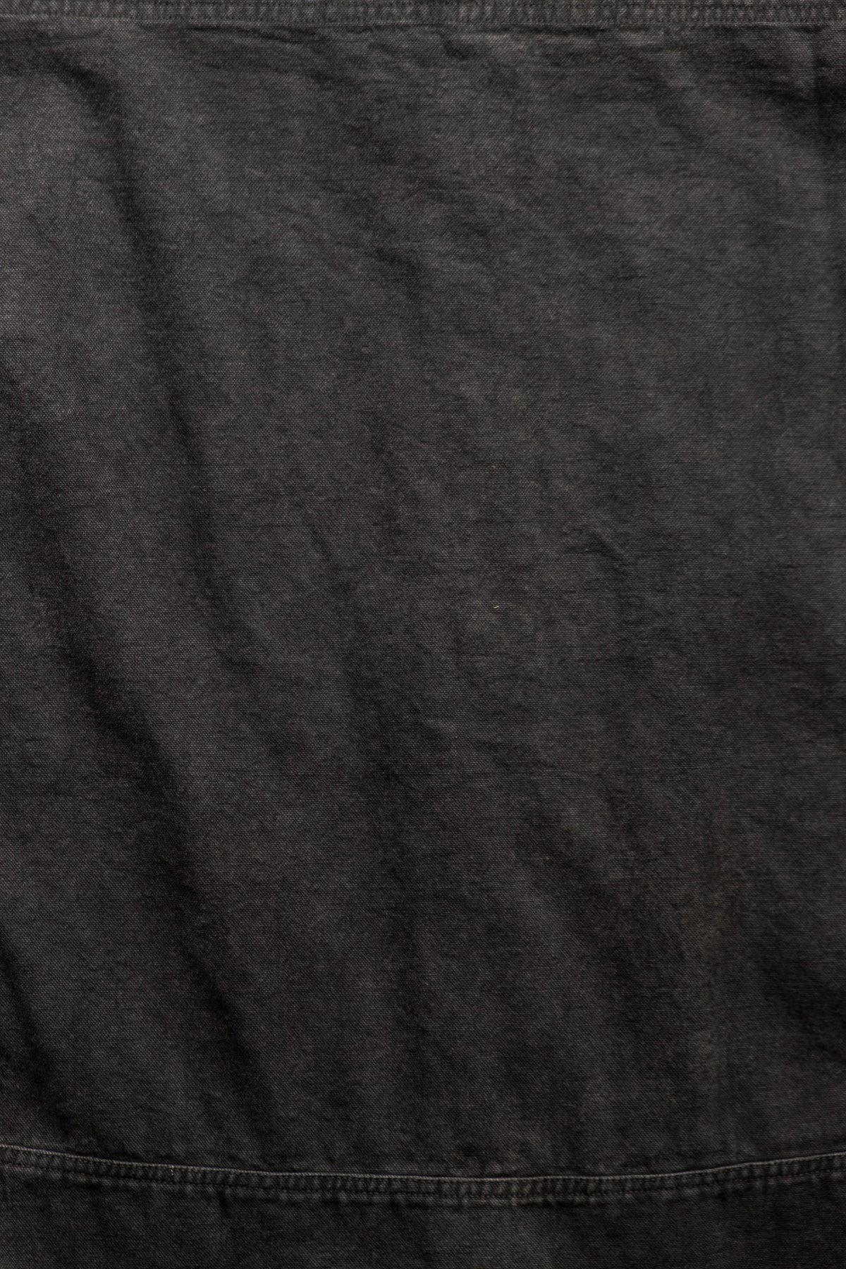 A close-up of dark charcoal gray fabric with visible texture and stitching.