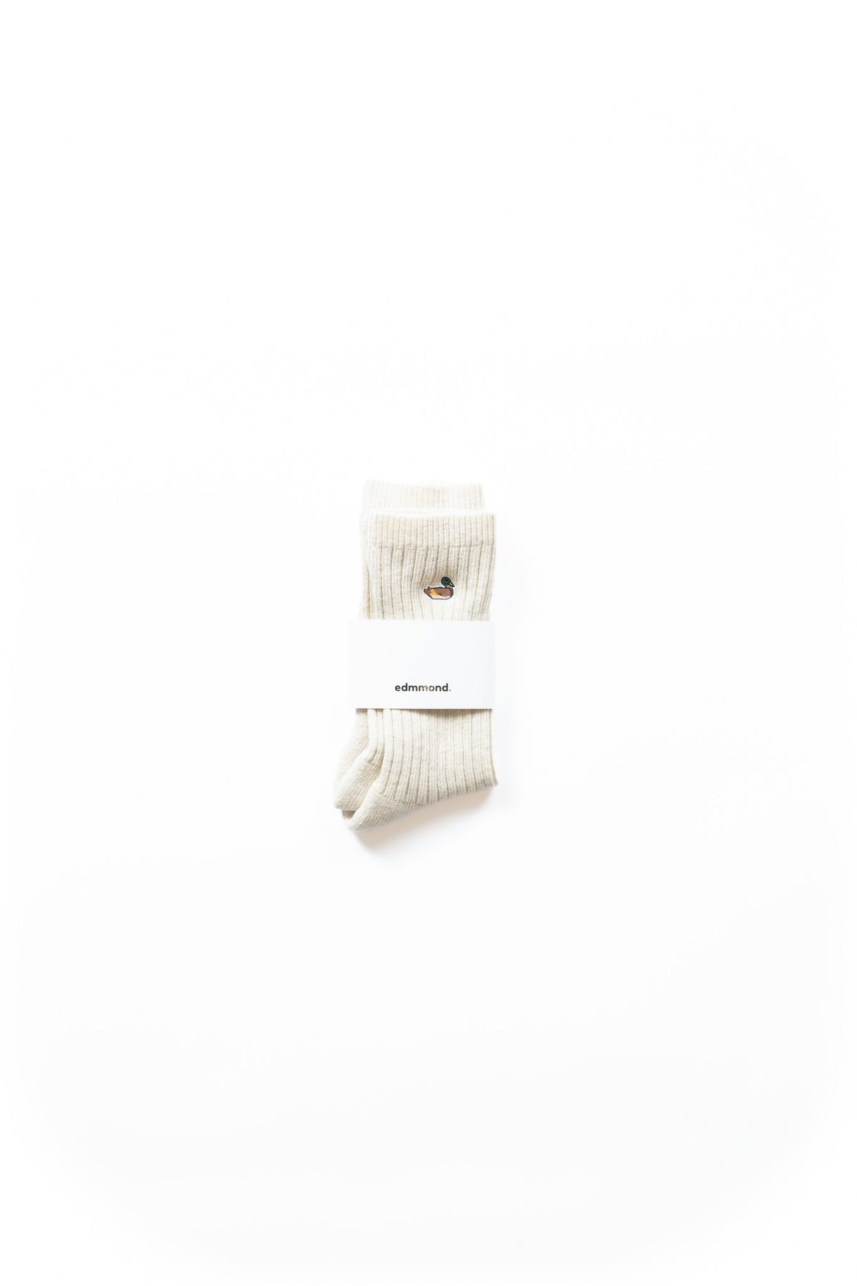 A pair of light grey ribbed crew socks with a small embroidered duck logo on the cuff, wrapped in a white paper 