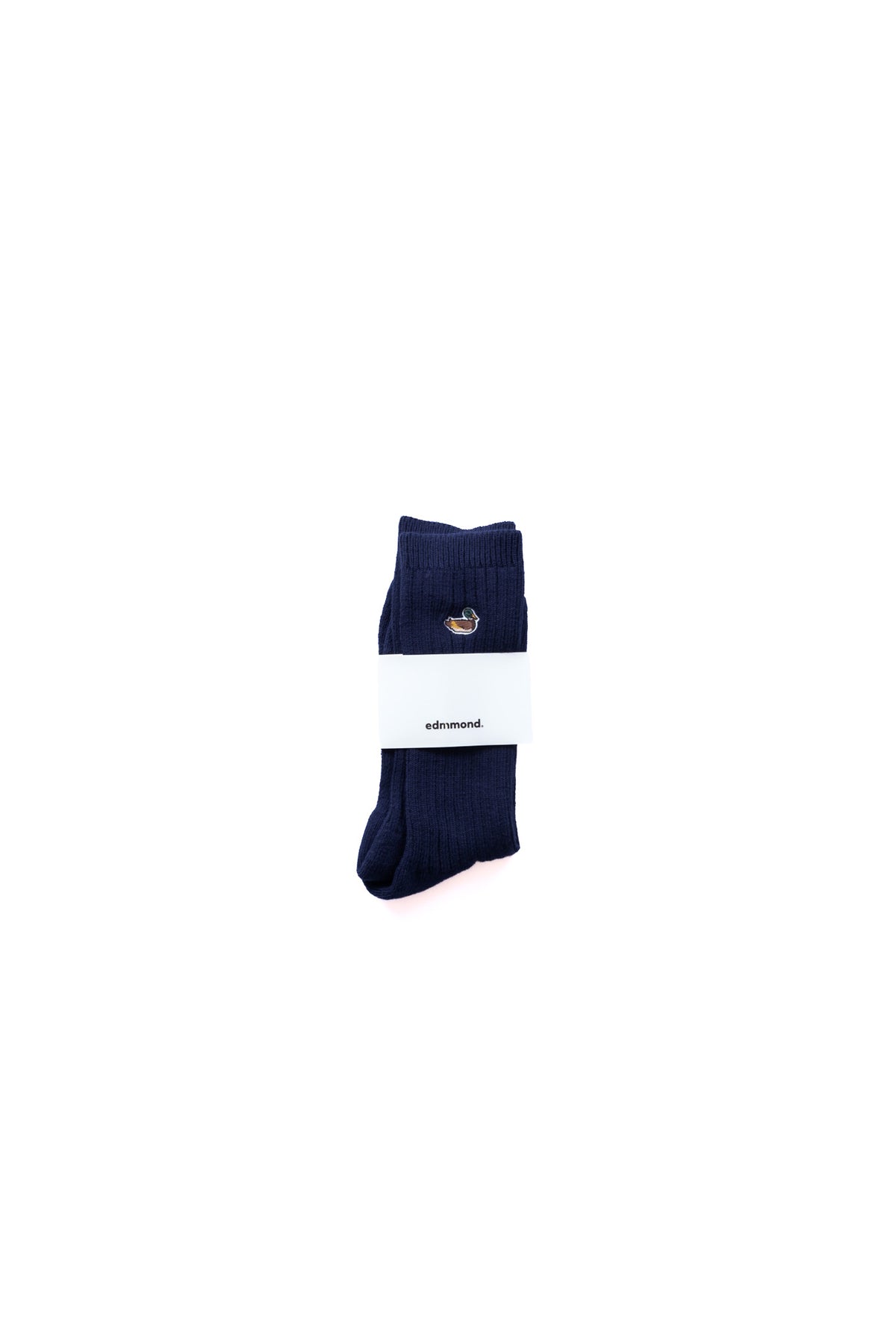 A pair of dark navy blue ribbed crew socks with a small embroidered duck logo on the cuff, wrapped in a white paper