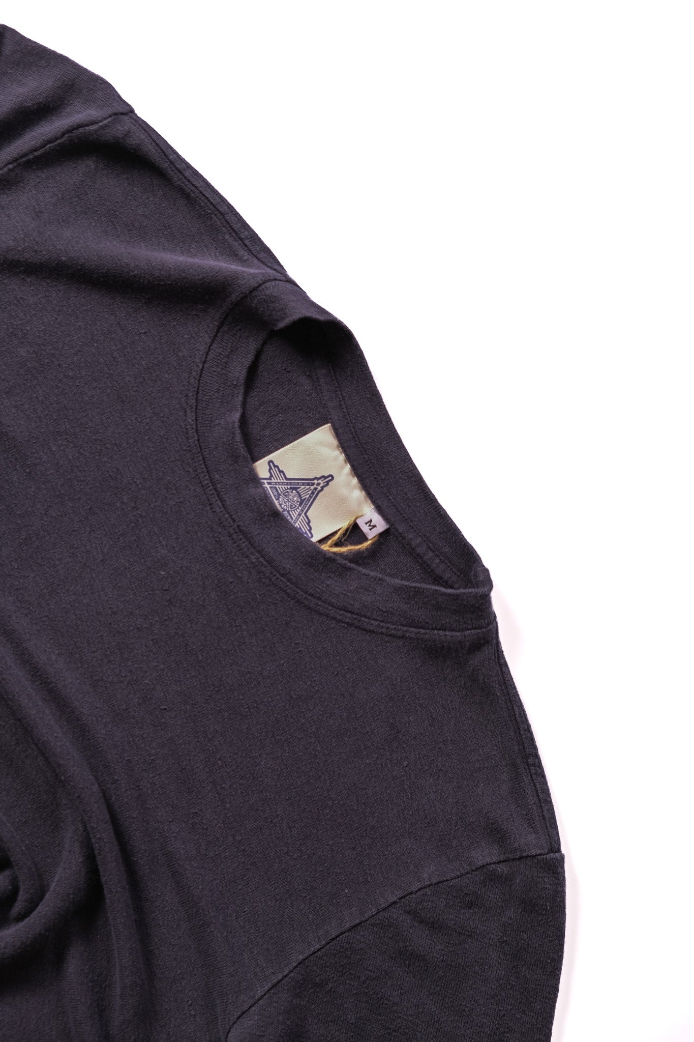 Close-up of a navy t-shirt showing the inner neck label with a star logo, set against a plain white background.