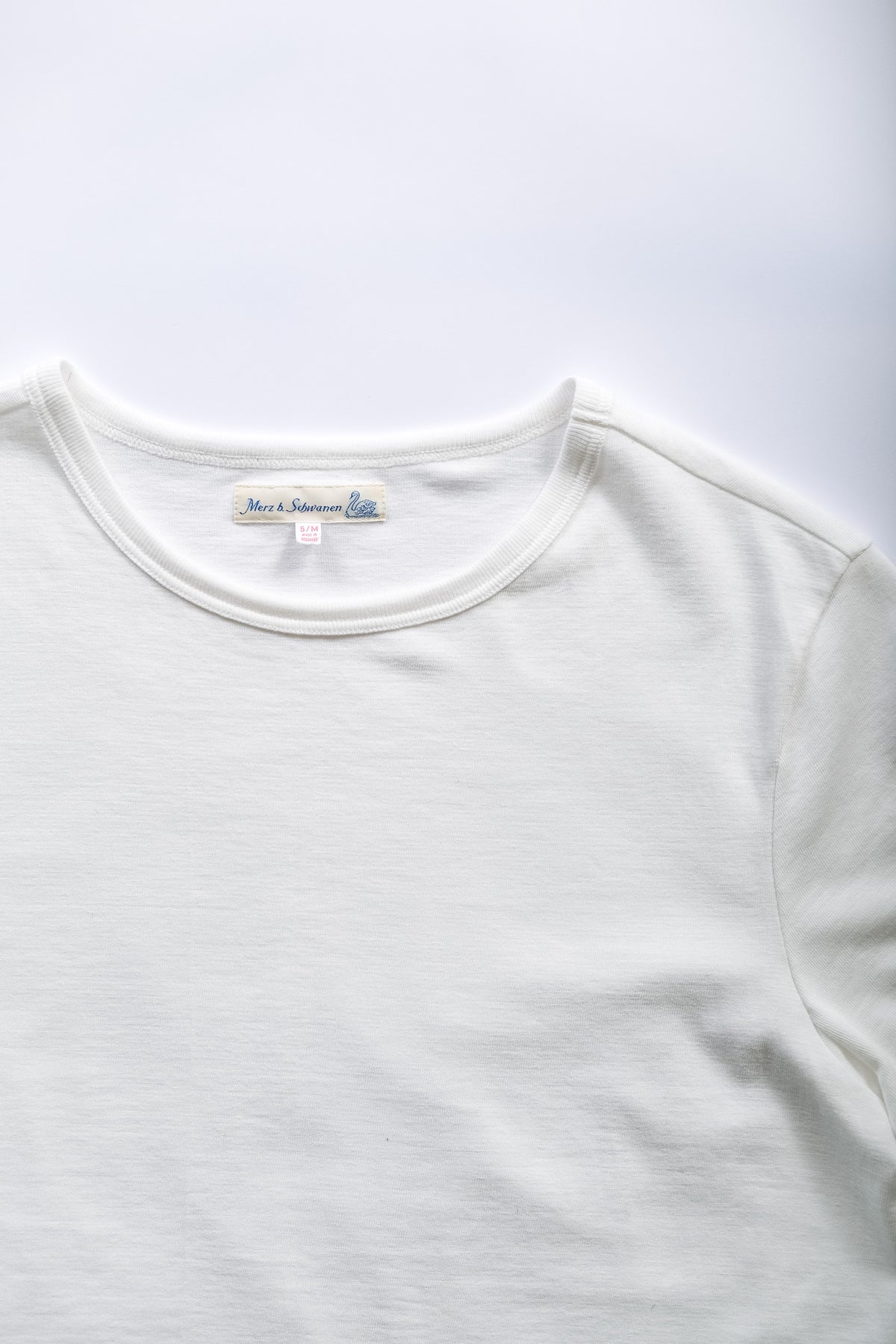 A close-up of a white crewneck t-shirt showing the inner neck label.