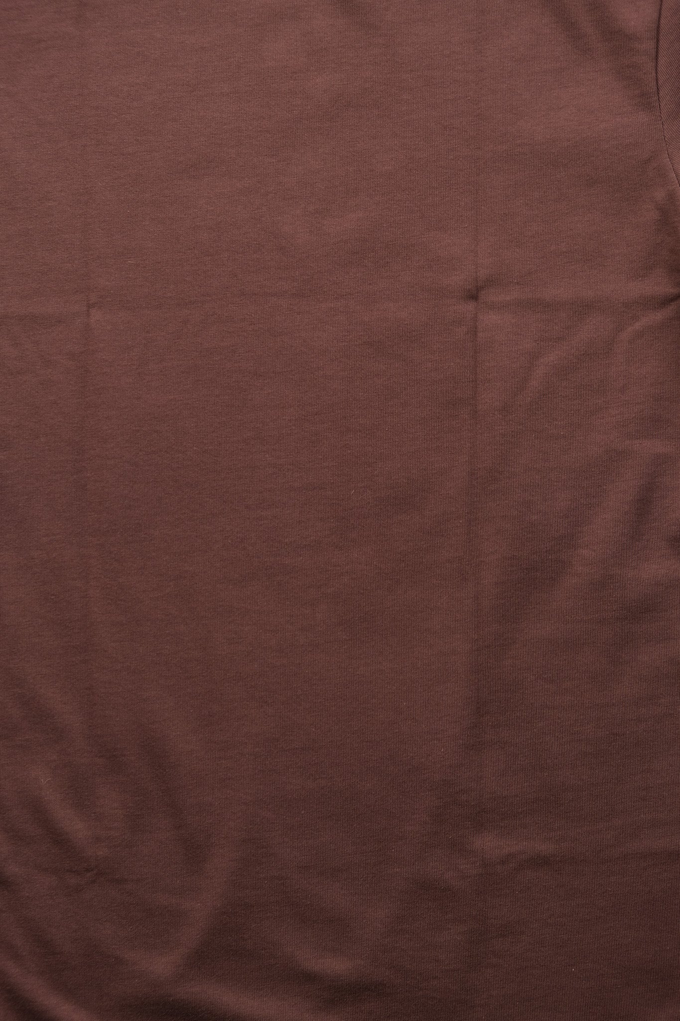 A close-up of a solid dark brown fabric texture with soft folds and wrinkles. detail shot