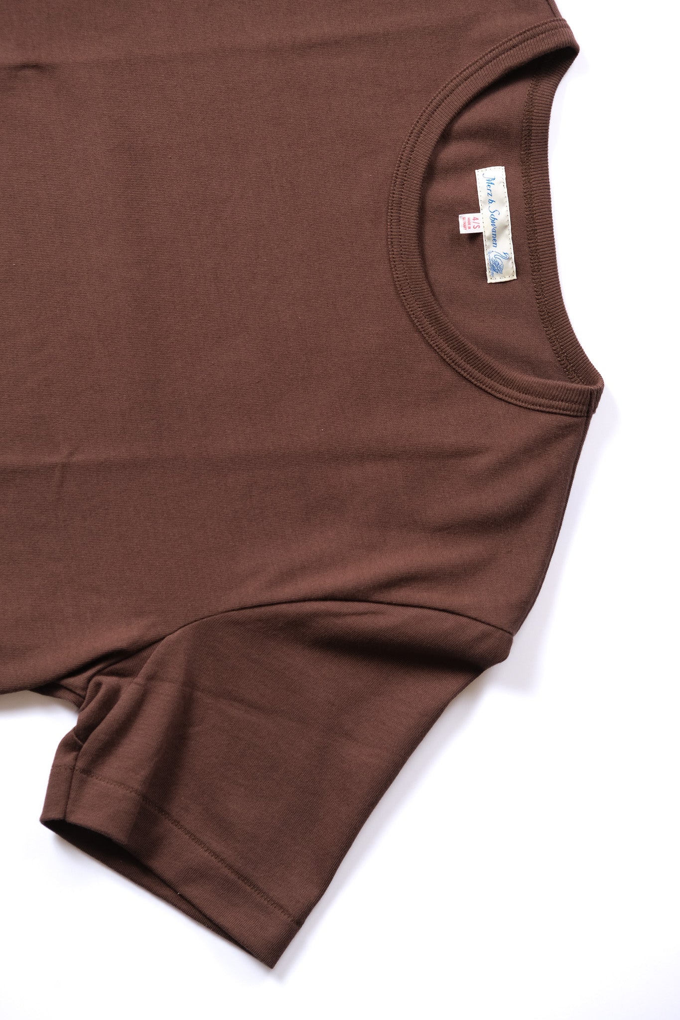 A close-up of a brown short-sleeve t-shirt laid flat on a white background, showing the inner neck label.