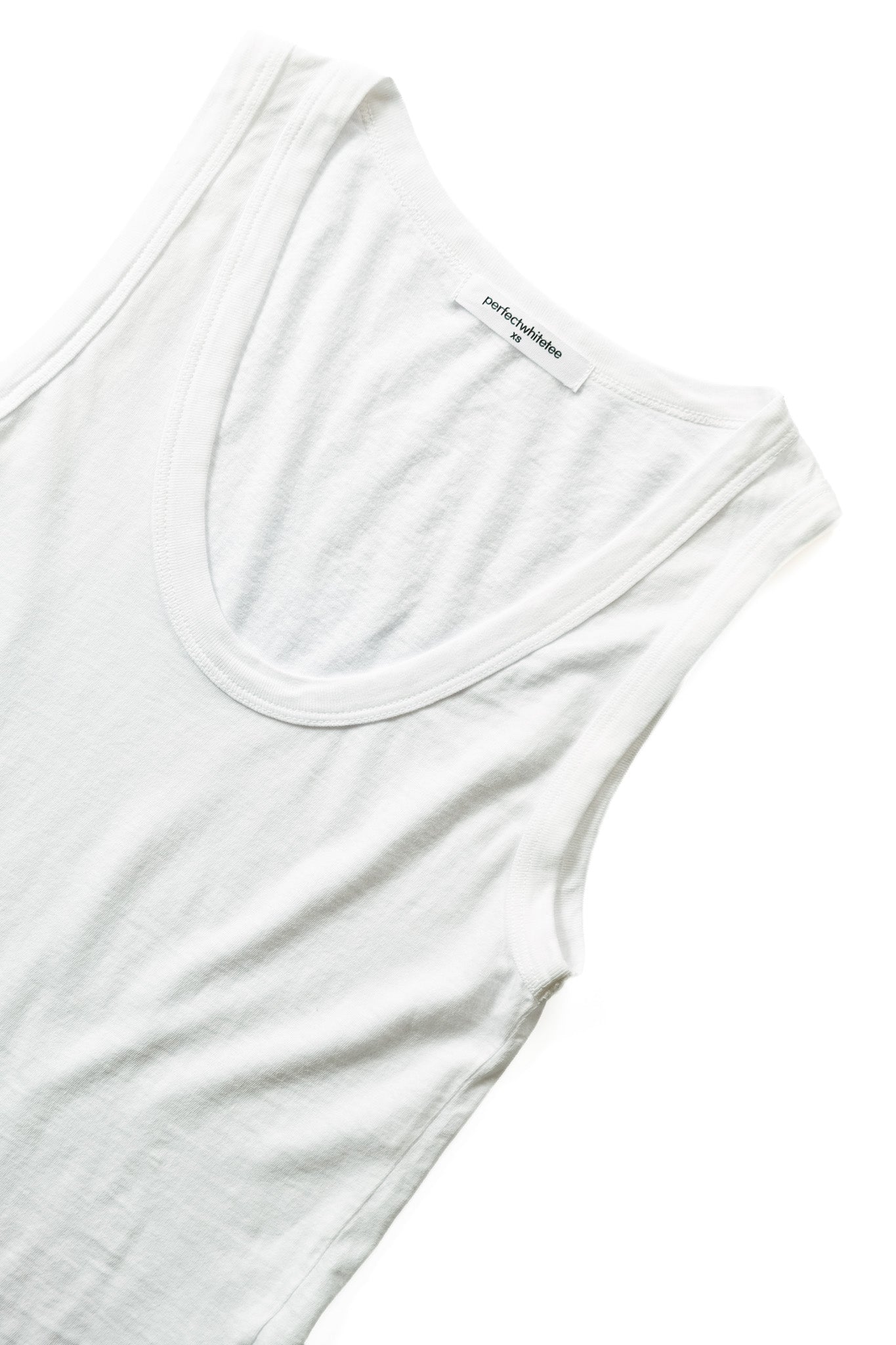 A close-up of a white tank top showing the scoop neck, ribbed collar trim