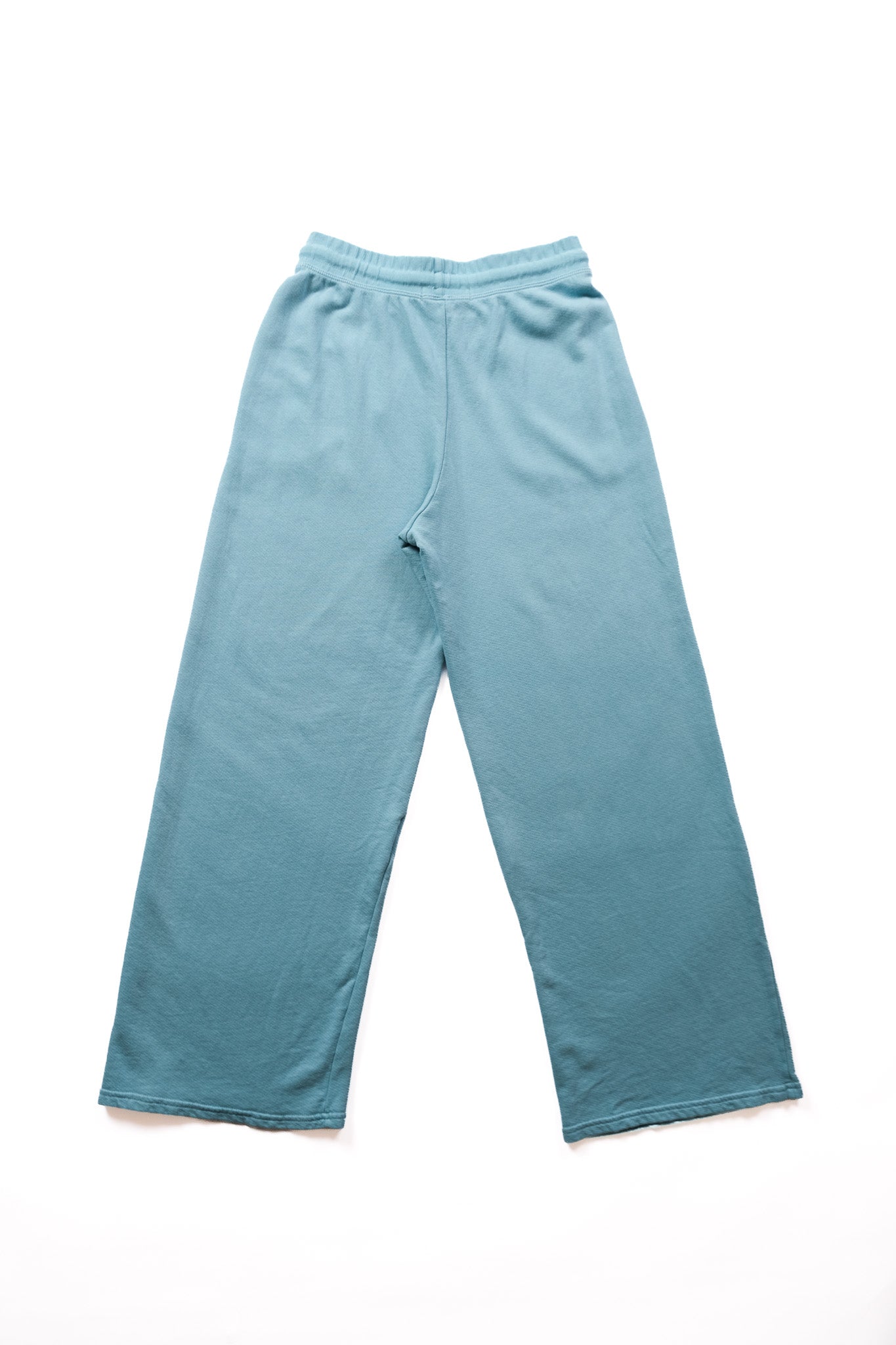 A pair of wide-leg sweatpants in a dusty teal blue color, laid flat on a white background.