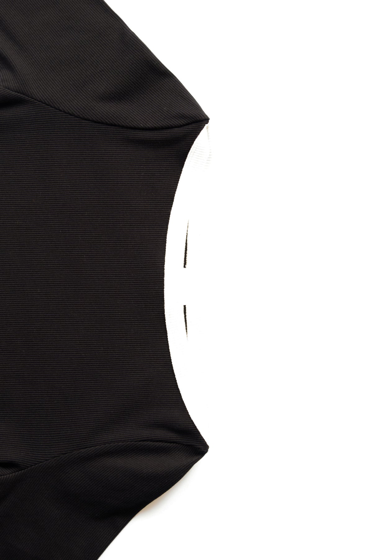 Close-up detail of a black ribbed garment, showing the side seam and curved neckline against a plain white background.