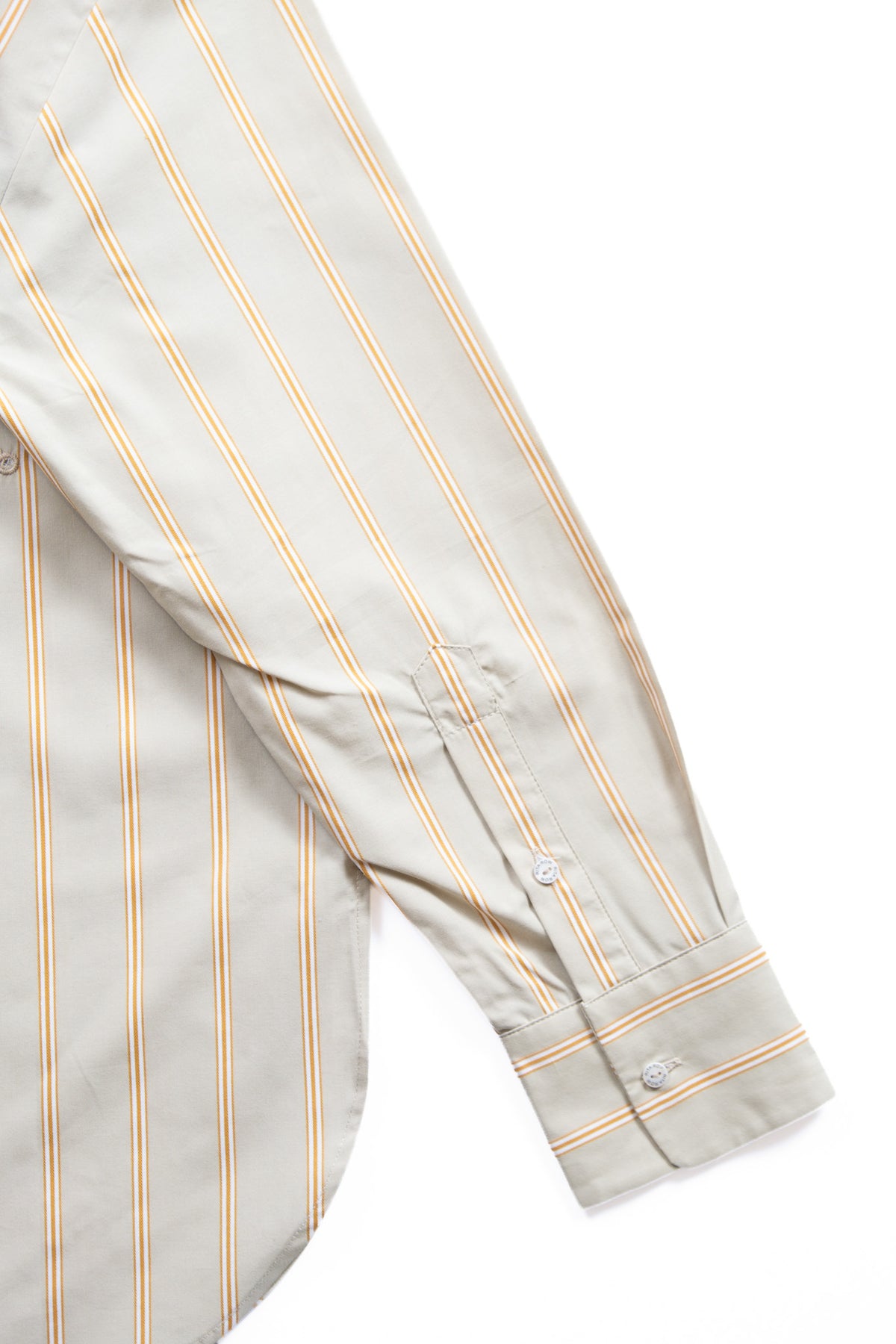 Close-up of a long-sleeve button-up shirt with vertical thin stripes in caramel and white on a light green base, showing the cuff and buttons against a white background.